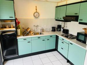 una cocina con armarios azules y un reloj en la pared en gite campagne Aupthiesomme au calme entre terre et mer, en Brailly-Cornehotte