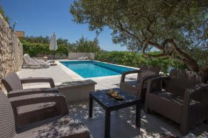 a swimming pool with chairs and a table next to a table sidx sidx at Apartments Niana with heated swimingpool in Okrug Donji