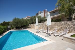 a swimming pool with lounge chairs and umbrellas at Apartments Niana with heated swimingpool in Okrug Donji