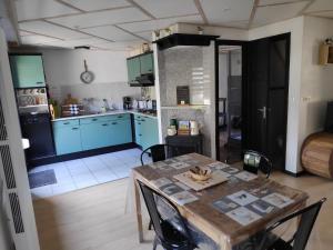 Una cocina con gabinetes azules y una mesa y sillas. en gite campagne Aupthiesomme au calme entre terre et mer, en Brailly-Cornehotte