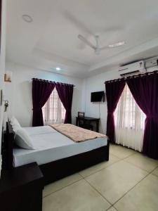 a bedroom with a large bed with purple curtains at Le Zaina's Fort Hotel in Cochin