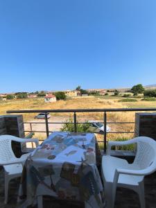 a table and chairs on a balcony with a view of a field at Eleonara Nea Koutali in Néa Koútali