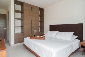 a bedroom with a large white bed with a wooden headboard at Akumal LuumHa Private Hot tub 7 Rooftop Pools Beach Access in Akumal