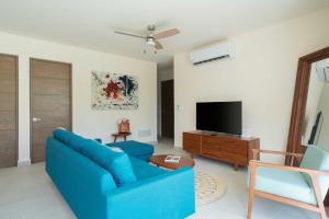a living room with a blue couch and a tv at Akumal LuumHa Private Hot tub 7 Rooftop Pools Beach Access in Akumal