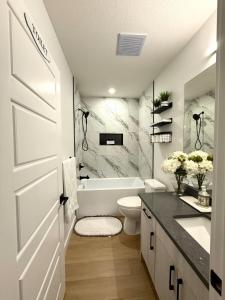 a white bathroom with a toilet and a sink at Luxe Stay with a Designer Touch in Calgary