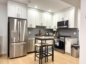 a kitchen with a stainless steel refrigerator and a table at Luxe Stay with a Designer Touch in Calgary