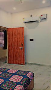 Zimmer mit einem Bett und einer Holztür in der Unterkunft Mahadev homestay Near Ram mandir and saryu Ghat in Ayodhya
