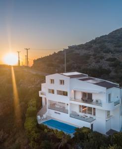 a white house with a sunset in the background at Sea View Residence Panorama Villa in Saronida