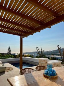 a wooden table with chairs under a wooden pergola at thEros - apartment 2 in Parikia