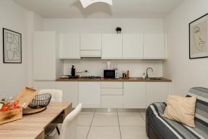 a kitchen with white cabinets and a table and a couch at Appartment - Joile Maisone in Porto Torres