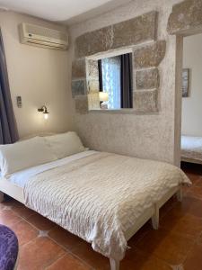 a bed in a bedroom with a stone wall at Hotel Villa Perla Di Mare in Budva