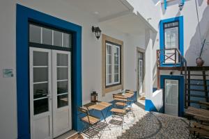 a patio with chairs and tables in a building at Casas da villa - Apartments in Ericeira