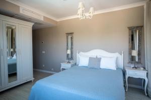 a bedroom with a blue bed with two tables and two mirrors at Eritrina Alacati in Alacati