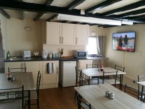 a kitchen with tables and chairs in a room at Guesthouse At Rempstone in Loughborough