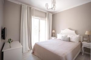 a white bedroom with a bed and a window at Eritrina Alacati in Alacati