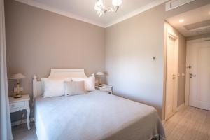 a bedroom with a white bed and a chandelier at Eritrina Alacati in Alacati