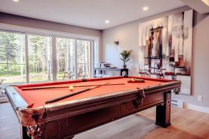 a pool table in a living room with a pool at Modern Waterfront Cottage on the Rouge River & Spa in Rivière-Rouge