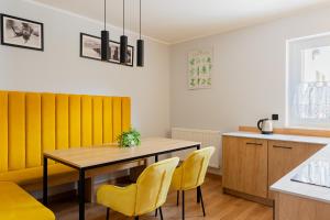 a dining room with a table and yellow chairs at Fajne Apartamenty - Karwia - Blisko Plaży - Komfort i Cisza in Karwia
