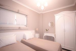 a white bedroom with two beds and a window at Eritrina Alacati in Alacati