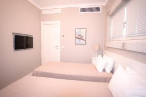 a white room with two beds and a tv at Eritrina Alacati in Alacati