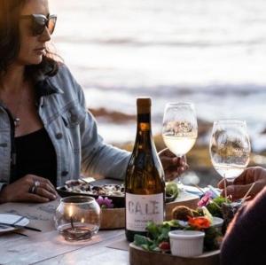 a woman sitting at a table with a bottle of wine at Casa Grande en Pichilemu, playa caminando a 5 min in Pichilemu