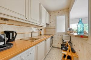 a kitchen with white cabinets and a sink and a window at Cocon Cosy Lumineux Avec Balcon Plage Et Gare À Pied in Bandol
