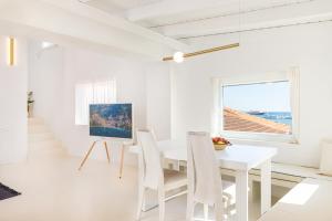 a white dining room with a white table and chairs at Calma Bianca in Pythagoreio