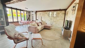 a living room with a couch and chairs and a tv at Le Mas des Cerisiers in Le Temple-sur-Lot