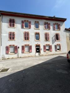 a white building with red shuttered windows on a street at Haut' Valentin in Pontarlier
