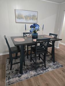 a black dining room table with chairs and a vase of flowers at The Miller's Retreat in Dothan