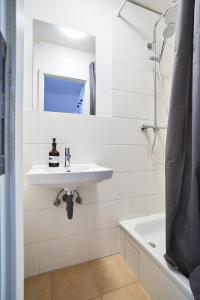 a white bathroom with a sink and a bath tub at Ruhiges zentrales Maisonette-Loft in Berlin in Berlin