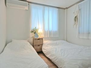 two beds in a white room with a window at 경주스테이구황,주차2대,스텐바이미,마샬스피커,다이슨에어랩,황리단길과 경주월드 관광에 위치 최상 in Gyeongju