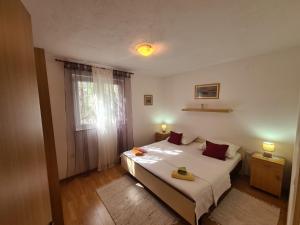 a bedroom with a bed and a window at Apartmani Uvodić in Rogoznica