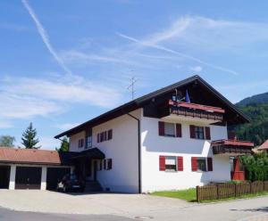 a white building with a black roof and red windows at Allgäu Moments Oberstaufen in Oberstaufen