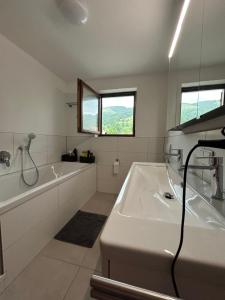 a white bathroom with a tub and a sink at Allgäu Moments Oberstaufen in Oberstaufen +17 photos