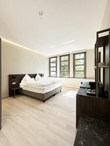 a white bedroom with a bed and a large window at The Treasury Hotel in Neuss