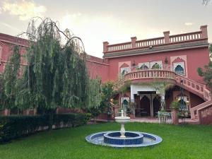 una grande casa rosa con una fontana nel cortile di Villa DALIA Route Ourika en Exclusivité a El Jemʼa Ghemat
