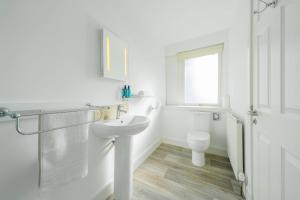 a white bathroom with a sink and a toilet at Taypark River View Apartment in Dundee
