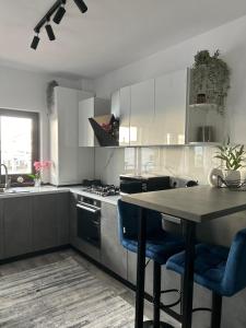 a kitchen with white cabinets and a table with blue chairs at CASAMORE Rentals in Braşov