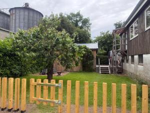 a wooden fence with a tree in a yard at Helle, große Unterkunft in ländlicher Umgebung in Sterup