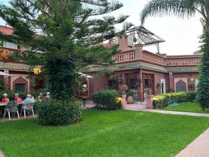 un gruppo di persone sedute a un tavolo di fronte a una casa di Villa DALIA Route Ourika en Exclusivité a El Jemʼa Ghemat