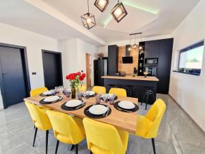 a dining room with a wooden table and yellow chairs at Luxury Villa Triton in Novalja