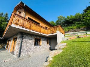 a house with a wooden balcony on top of it at Gîtes les COMBES in Saint-Léger-les-Mélèzes