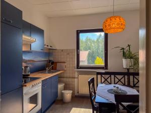 a kitchen with blue cabinets and a table and a window at Lieblingsplatz - Ferienwohnungen an der Liebesinsel in Mirow