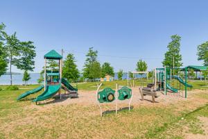 a playground with a bunch of playground equipment in a park at Walk to Manistee Lake Retro Cottage with Fire Pit! in Kalkaska