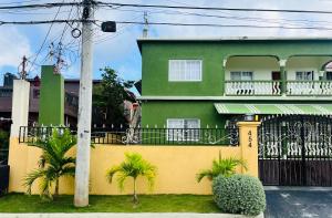 a green and yellow house with a fence and palm trees at Olive Breeze II in Runaway Bay