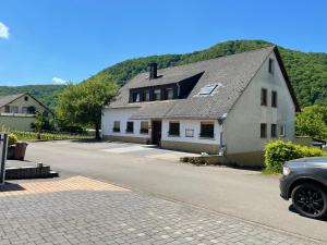 a white house with a black roof on a street at Pension Rieslingakademie in Mesenich