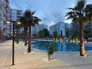 a large swimming pool with palm trees in a city at Sea View Mario's Studio in Sakës