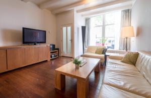 een woonkamer met een bank en een tv bij De Grote Sluis in Harlingen