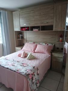 a bedroom with a large bed with pink sheets and pillows at Casa confortavel com 2 quartos Wi-Fi e estacionamento numero 1 in Curitiba